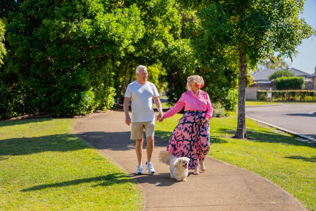 Senior couple walking their dog around an Oak Tree Retirement Village