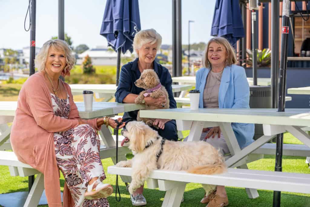 3 senior woman and two dogs enjoying spending time together at an Oak Tree Retirement Village