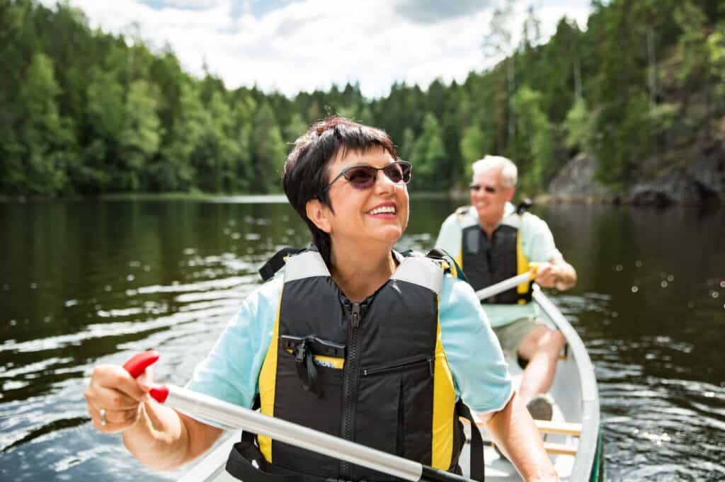Happy senior couple canoeing on a lake and enjoying the retirement lifestyle.