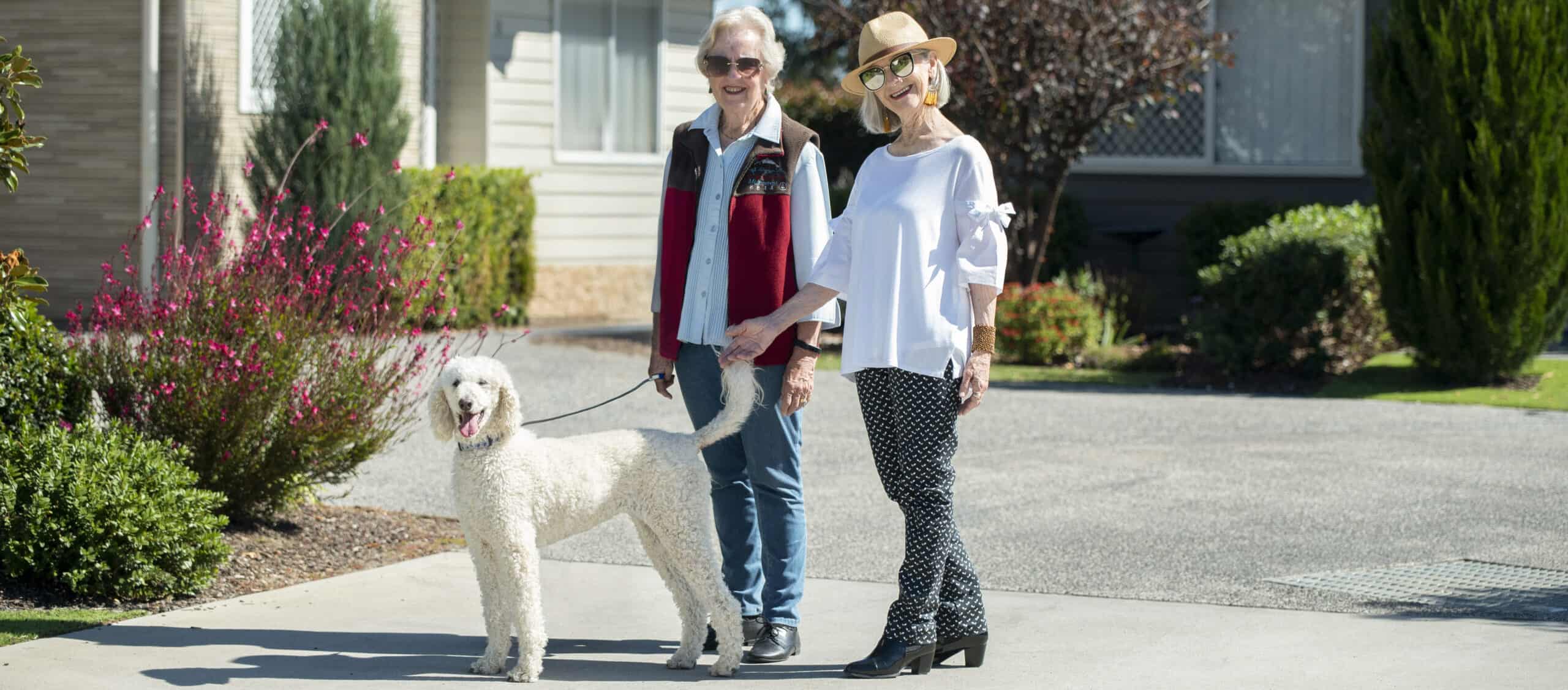 Two senior woman are walking their dog in Oak Tree Bathurst Retirement village