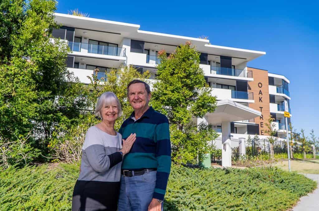 Conventional vs Retirement apartments, senior couple standing in front of Oak Tree Retirement properties.
