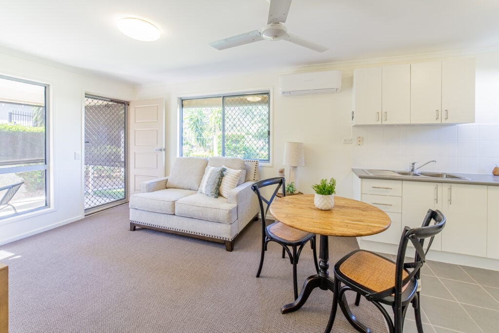 A compact kitchen, living room, and dining area in Goodna Villa 62, showcasing a modern, open-concept apartment layout.