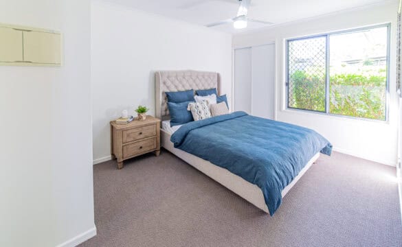 A bedroom in Goodna Villa 62 featuring a blue bed and a window, creating a cozy and inviting atmosphere.
