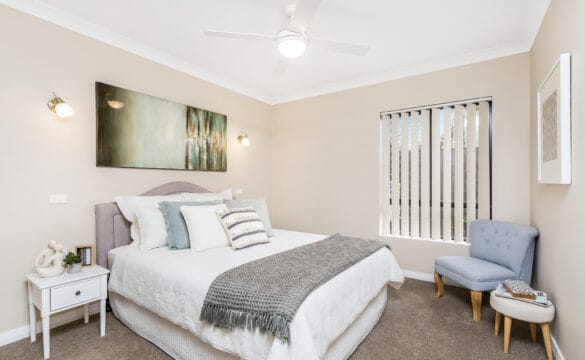 Modern bedroom with bed, chair and side tables in one of our Oak Tree Retirement Village Goonellabah Villas