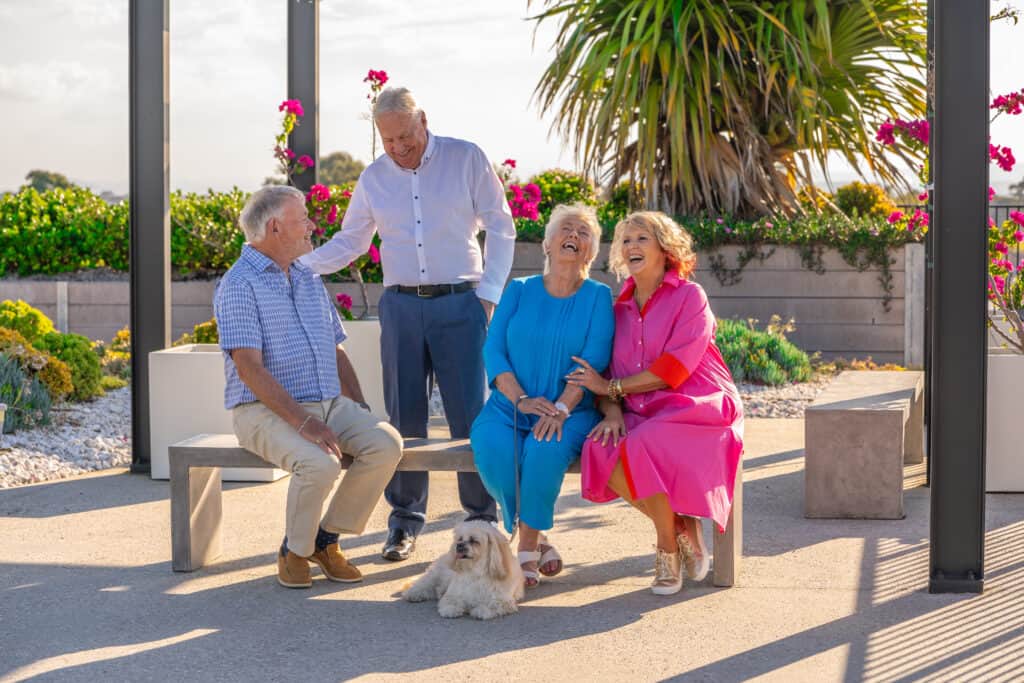 A group of seniors and a dog enjoying the outdoor space at one of our Oak Tree Retirement Village locations.