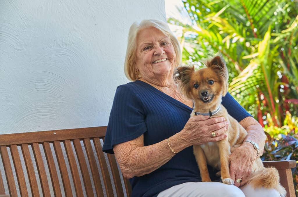 Pet friendly retirement village, senior woman smiles at the camera holding her dog.