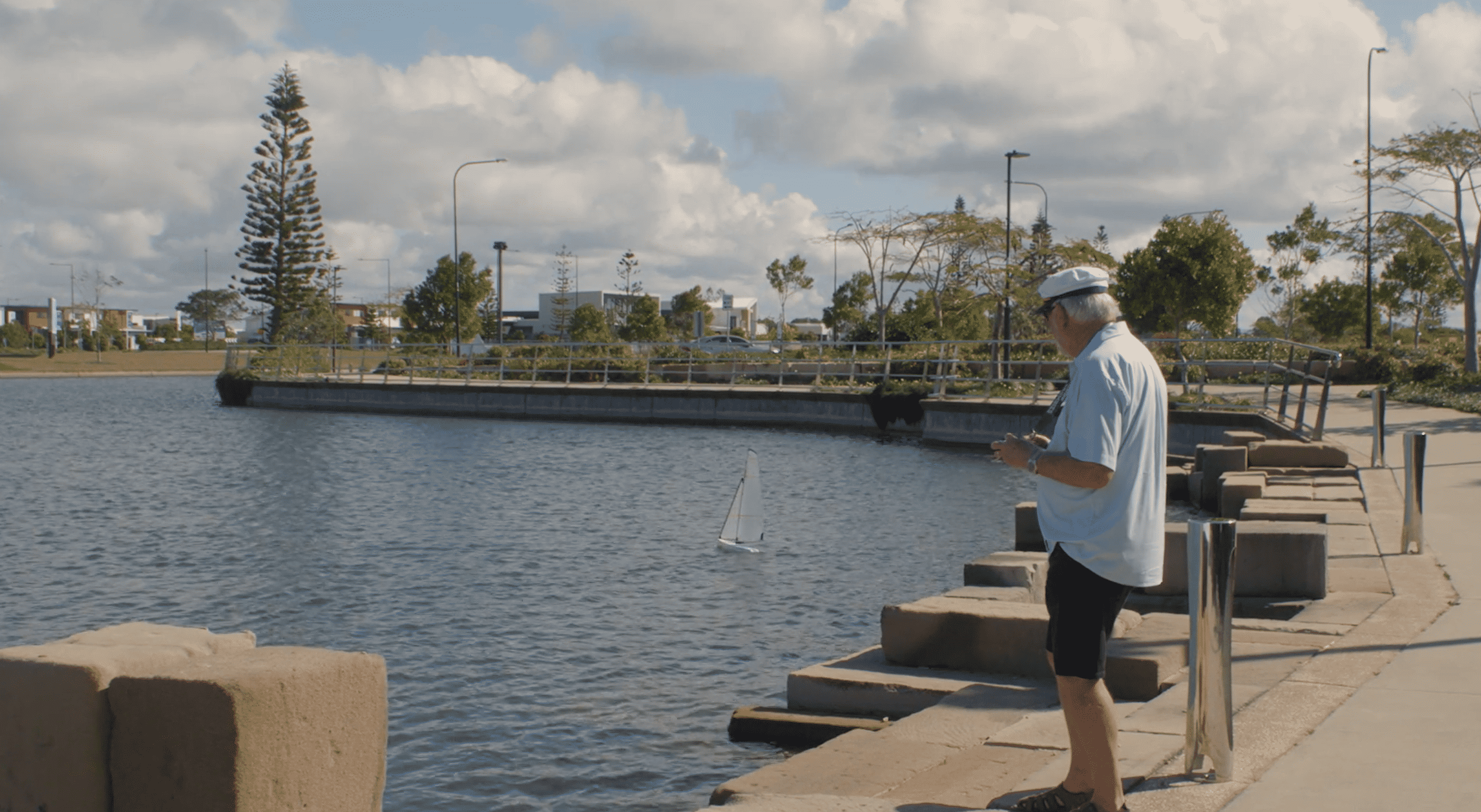 Senior man enjoying a remote control boat on a lake near one of our Oak Tree Retirement Villages.