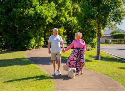 Senior couple walking their dog around an Oak Tree Retirement Village