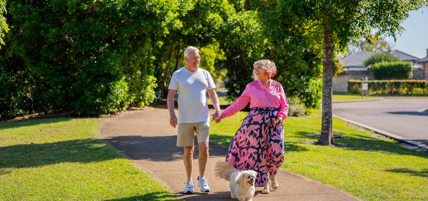 Senior couple walking their dog around an Oak Tree Retirement Village