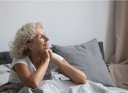 A smiling senior woman in bed after enjoying a good night sleep.