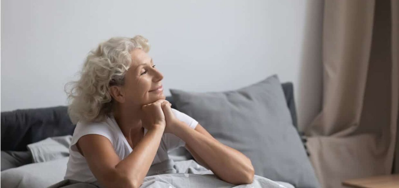 A smiling senior woman in bed after enjoying a good night sleep.