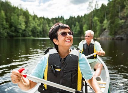 Happy senior couple canoeing on a lake and enjoying the retirement lifestyle.