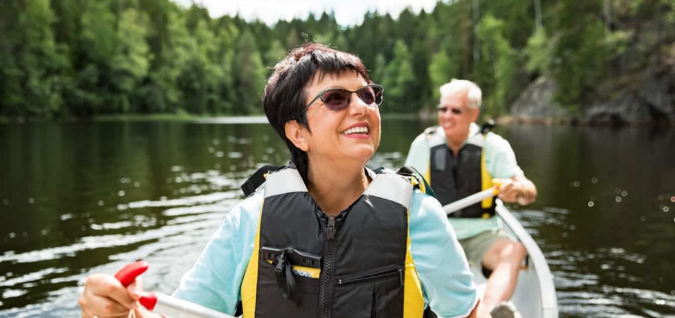 Happy senior couple canoeing on a lake and enjoying the retirement lifestyle.