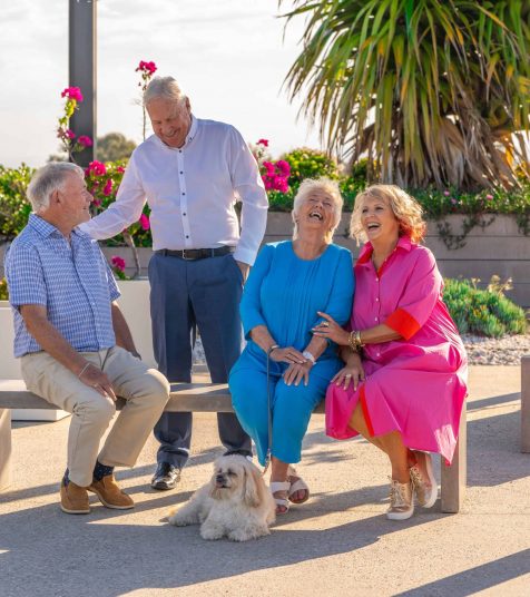 A group of seniors and a dog enjoying the outdoor space at one of our Oak Tree Retirement Village locations.