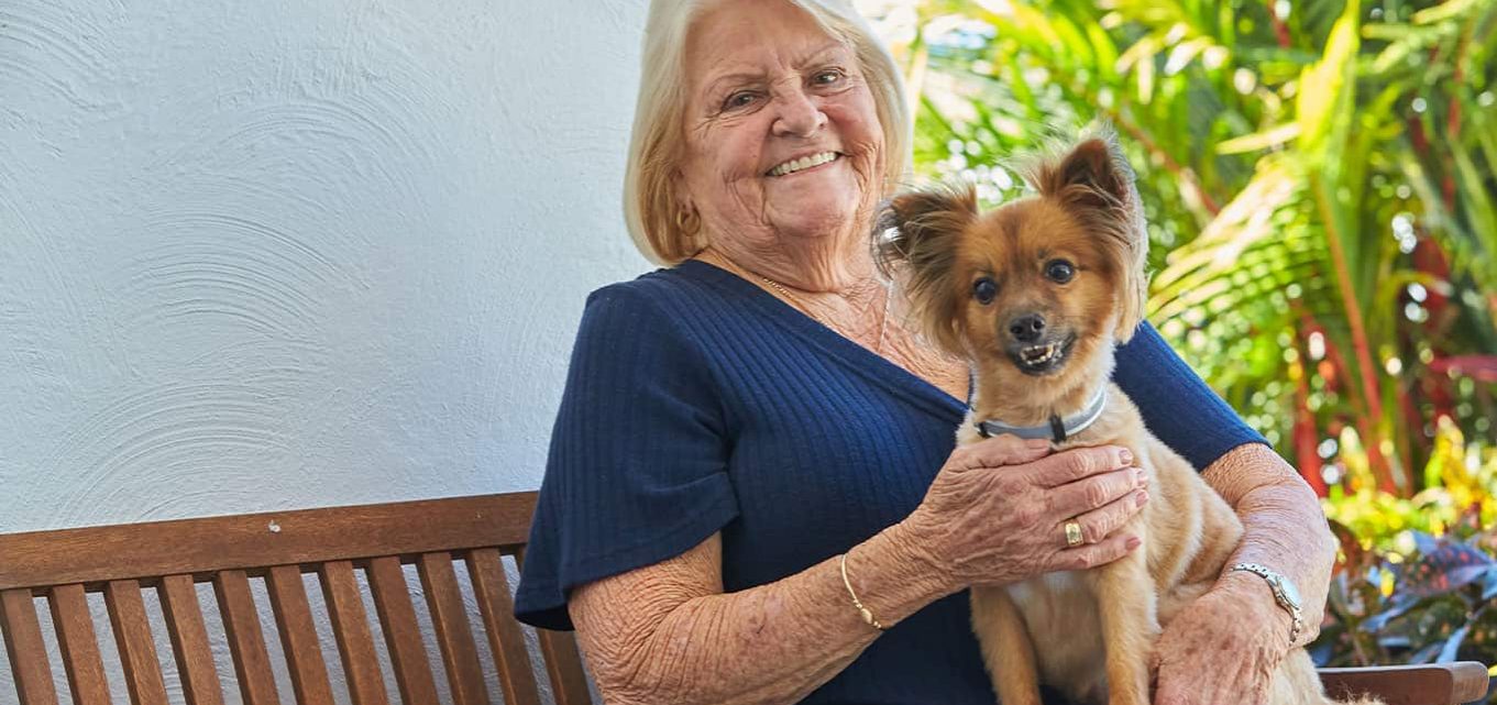 Pet friendly retirement village, senior woman smiles at the camera holding her dog.