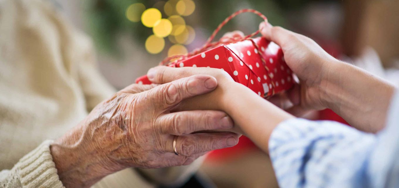A young person giving a senior person a gift at Christmas