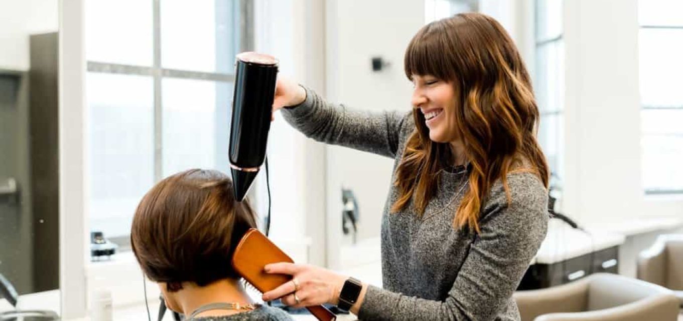 Young woman blowdrying and brushing the hair of an older woman