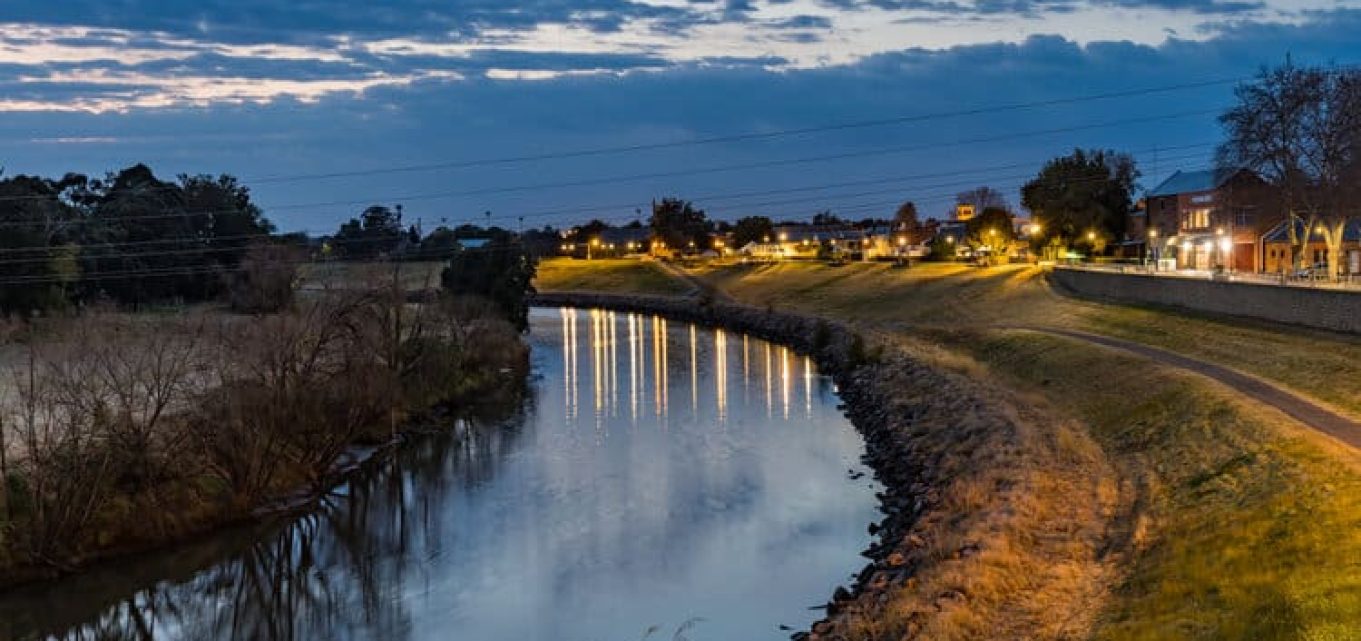 Rural river area in Rutherford at night with riverside buildings lit up.