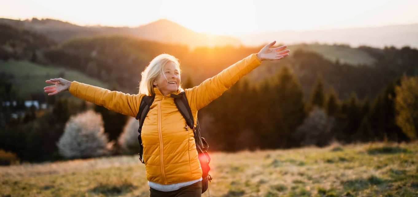 Woman wearing a yellow coat and enjoying exploring the countryside