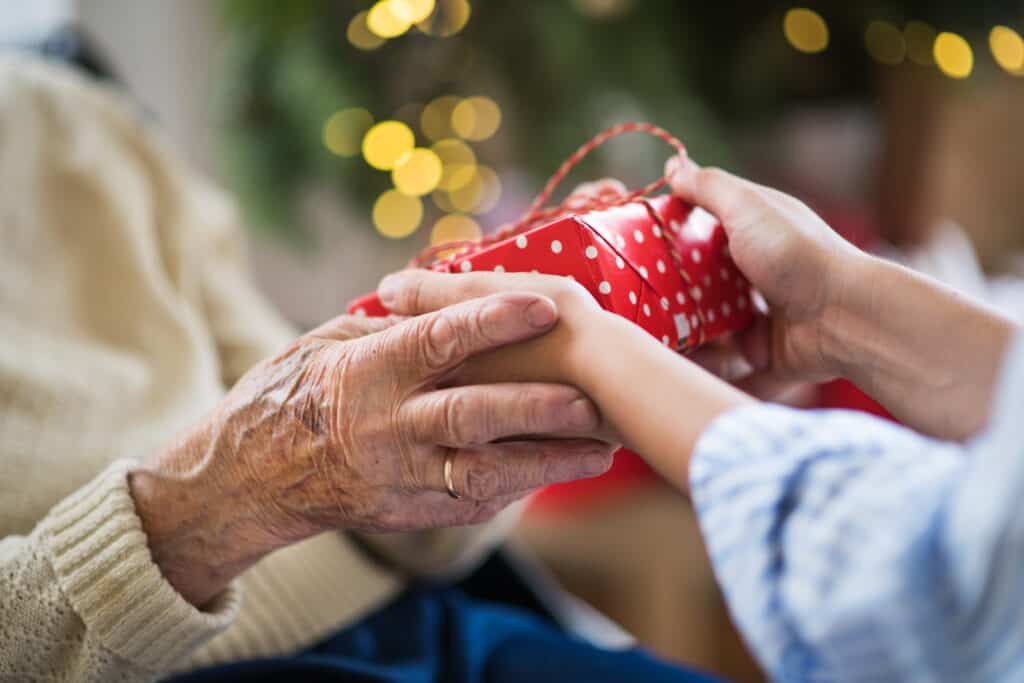A young person giving a senior person a gift at Christmas