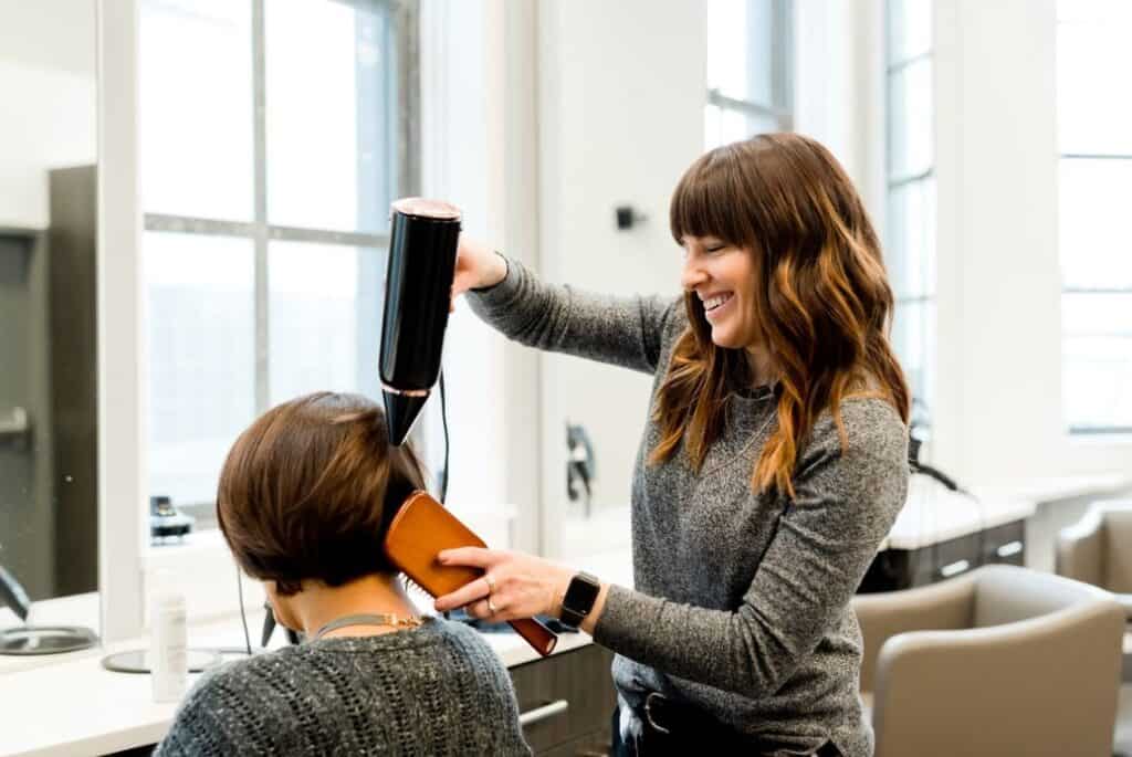 Young woman blowdrying and brushing the hair of an older woman