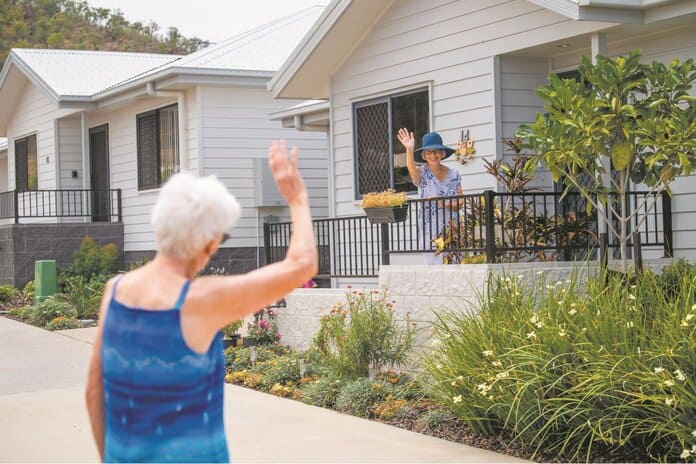 Two older women waving at each other from across the way in one of our Oak Tree Retirement Villages