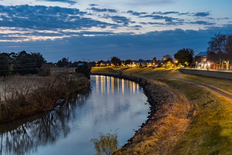 Rural river area in Rutherford at night with riverside buildings lit up.