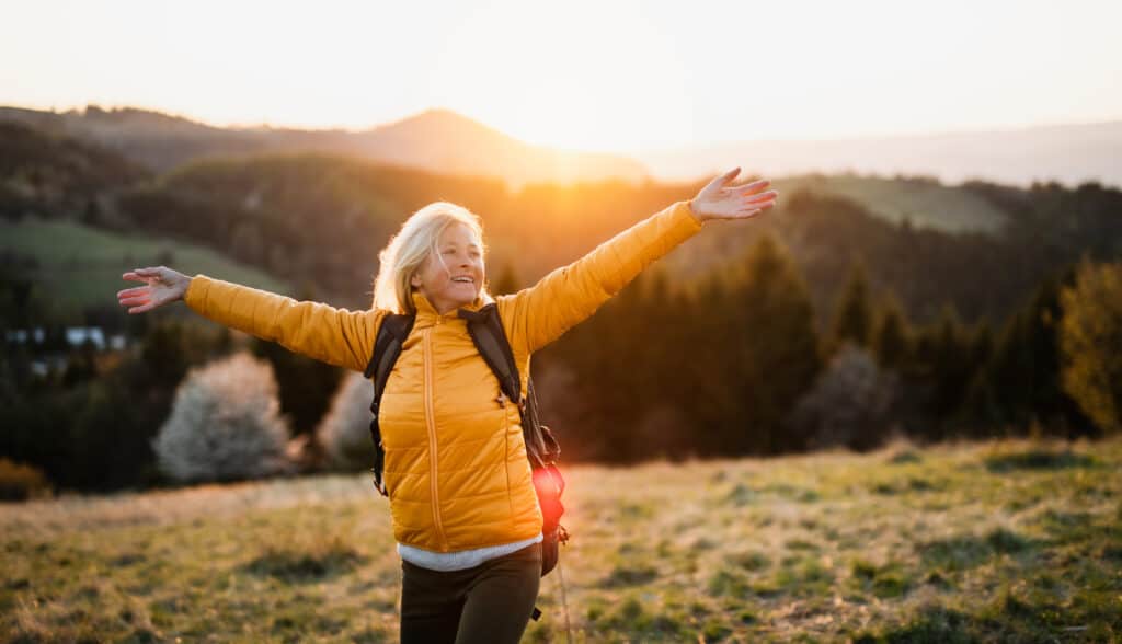 Woman wearing a yellow coat and enjoying exploring the countryside