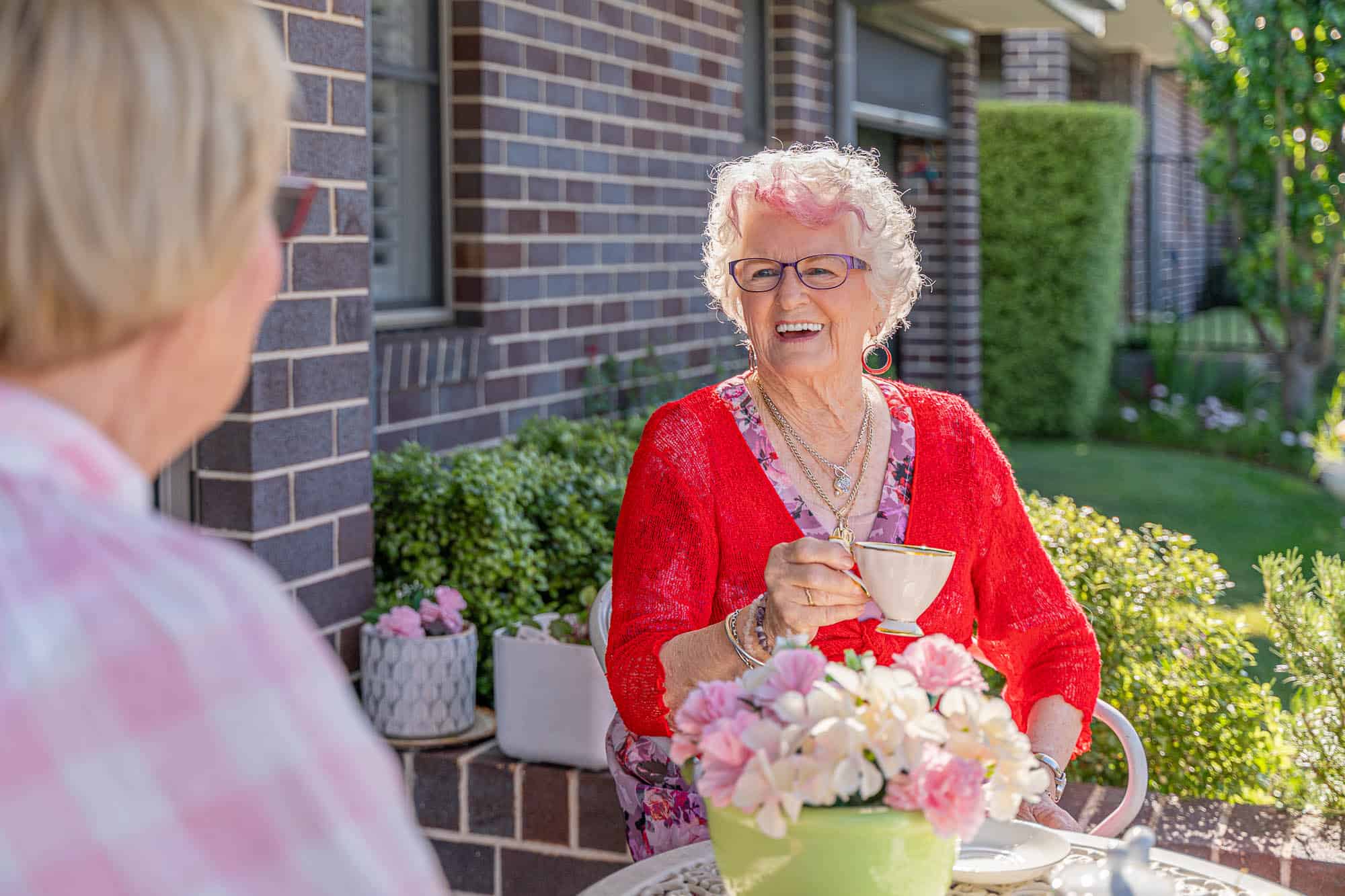 Senior woman in conversation with a friend outside her Oak Tree Retirement Village home